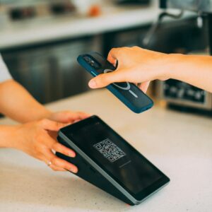 Close-up of a contactless payment using a smartphone and QR code scanner in a modern retail setting.