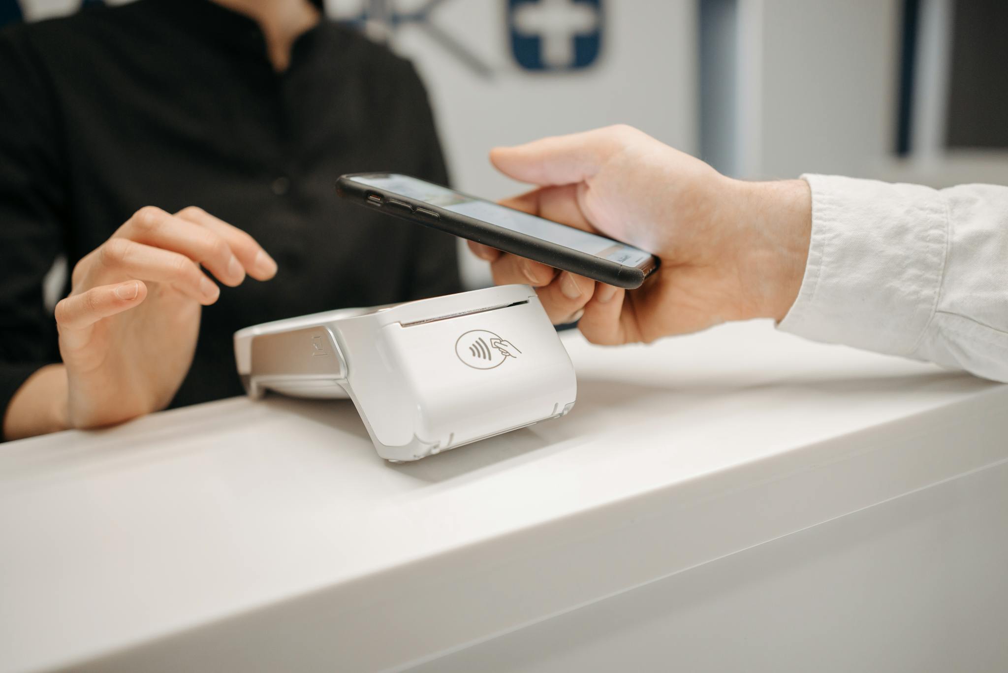Person using a smartphone for contactless payment at a retail counter, highlighting cashless convenience.